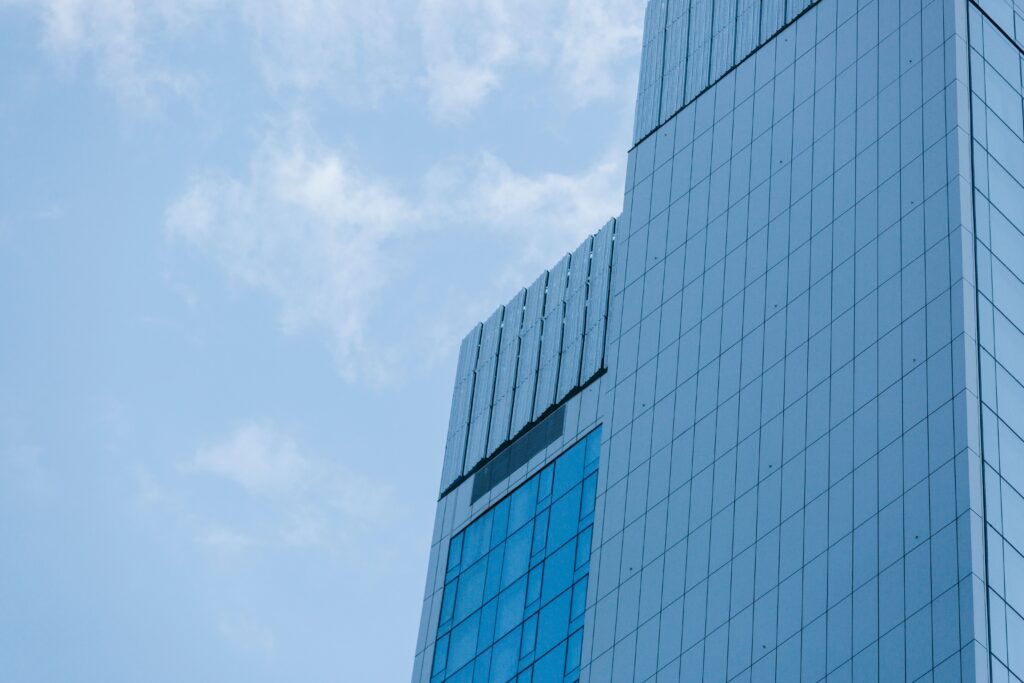 Low angle of contemporary skyscrapers with glass mirrored facades against cloudy blue sky on sunny day